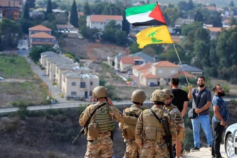 Tentara Lebanon berdiri di sebuah bukit menghadap Kota Metula di Israel ketika seorang pria mengibarkan bendera Palestina dan Hizbullah di Perbatasan Lebanon-Israel di Desa Selatan Kafr Kila, Lebanon, pada (9/10/2023) (Foto: Dok. Mohammed Zaatari/AP)
